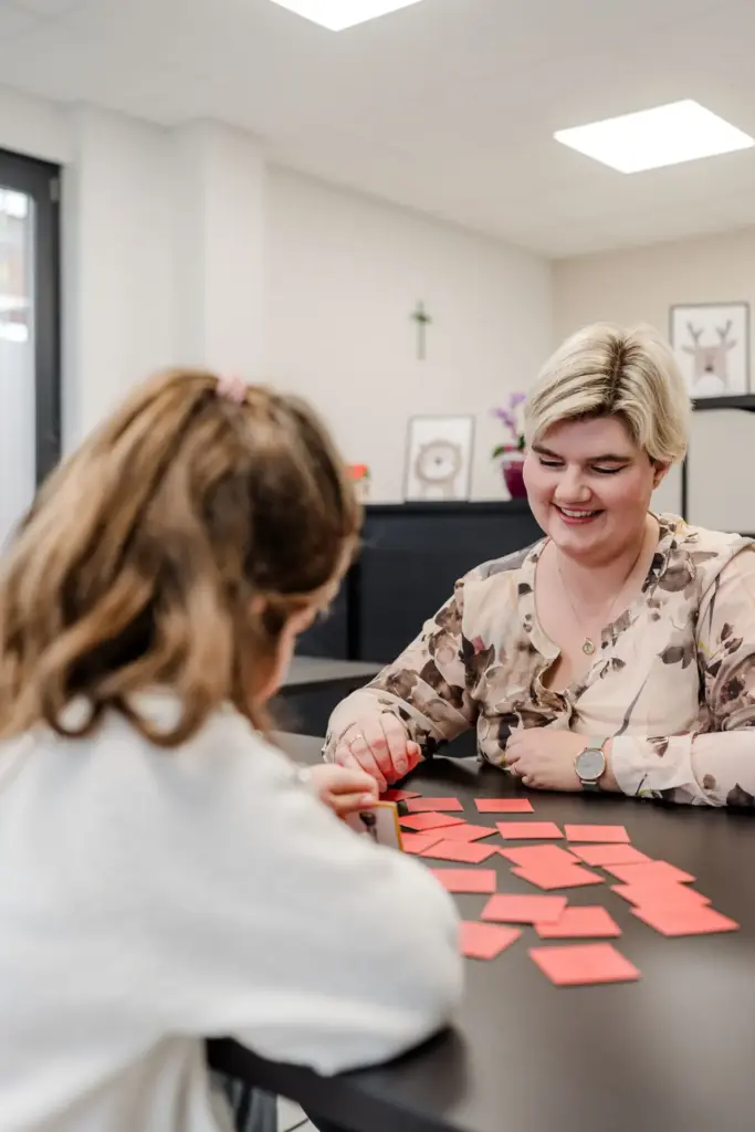 Monika Witzmann bei der Arbeit als Logpädin zusammen mit einem Kind sitzend an einem Tisch, rote Kärtchen vor den beiden, Praxis für Logopädie Monika Witzmann Kirchroth