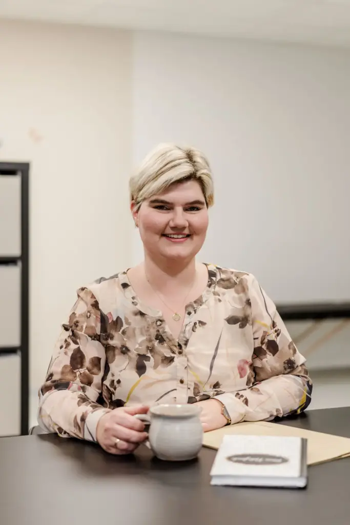 Monika Witzmann, Logopädin in Straubing-Bogen, sitzend an einem Tisch, Notizblock und Tasse vor sich